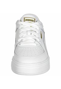 Zapatilla blanca de cuero con punta redonda, detalles perforados, lengüeta acolchada y cordones en forma cónica. Presenta un acento del logo en dorado en la lengüeta.