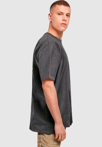 Siva bombažna majica s kratkimi rokavi, sproščenega kroja in okrožnim izrezom. Opozorljivi šivi in teksturirana tkanina.