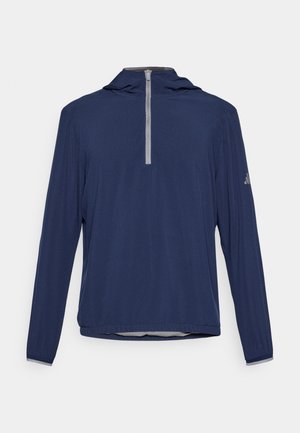 Navy long-sleeve pullover with a half-zip front, textured fabric, and a hood. Features a grey accent at the zipper and logo on the sleeve.