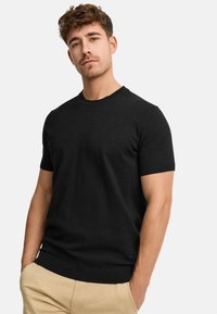Schwarzer Kurzarm-Pullover aus leichtem Strick, mit Rundhalsausschnitt und gerippten Bündchen. Auffällig durch sein einfaches Design und die Textur.