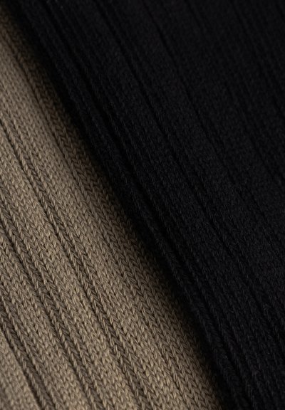 Gros plan sur un tissu en maille côtes noir et beige, montrant des motifs verticaux texturés et des points.