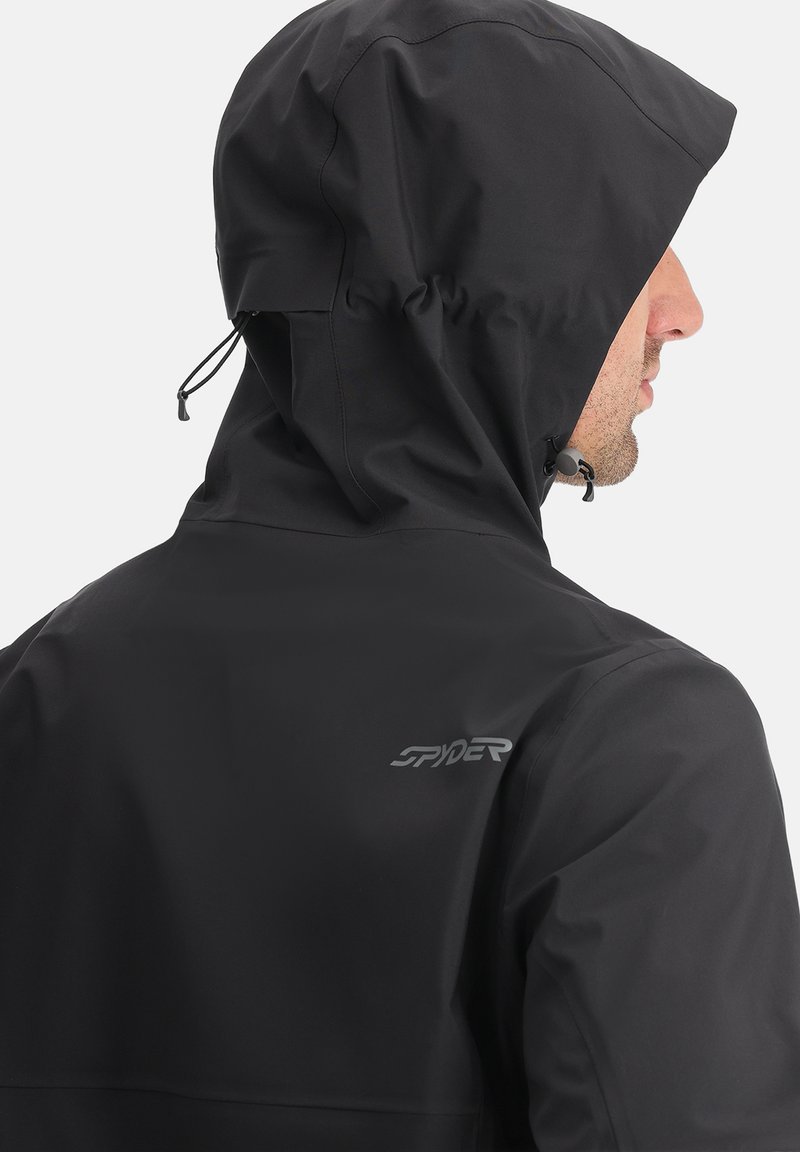 Czarna wodoodporna kurtka z dopasowaną kapturem. Posiada sznurek do regulacji, gładką fakturę oraz subtelne logo z tyłu. Nowoczesny sportowy design.