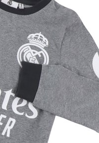 Graues Langarmshirt mit schwarzem Kragen, das mit einem weißen Logo, einem Krondetail und dem Text "Emirates Fly Better" prominent bedruckt ist.