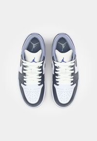 Baskets blanches et bleu marine à faible hauteur. Présentent un embout perforé, des lacets blancs et des accents gris avec un logo Jumpman sur la languette.