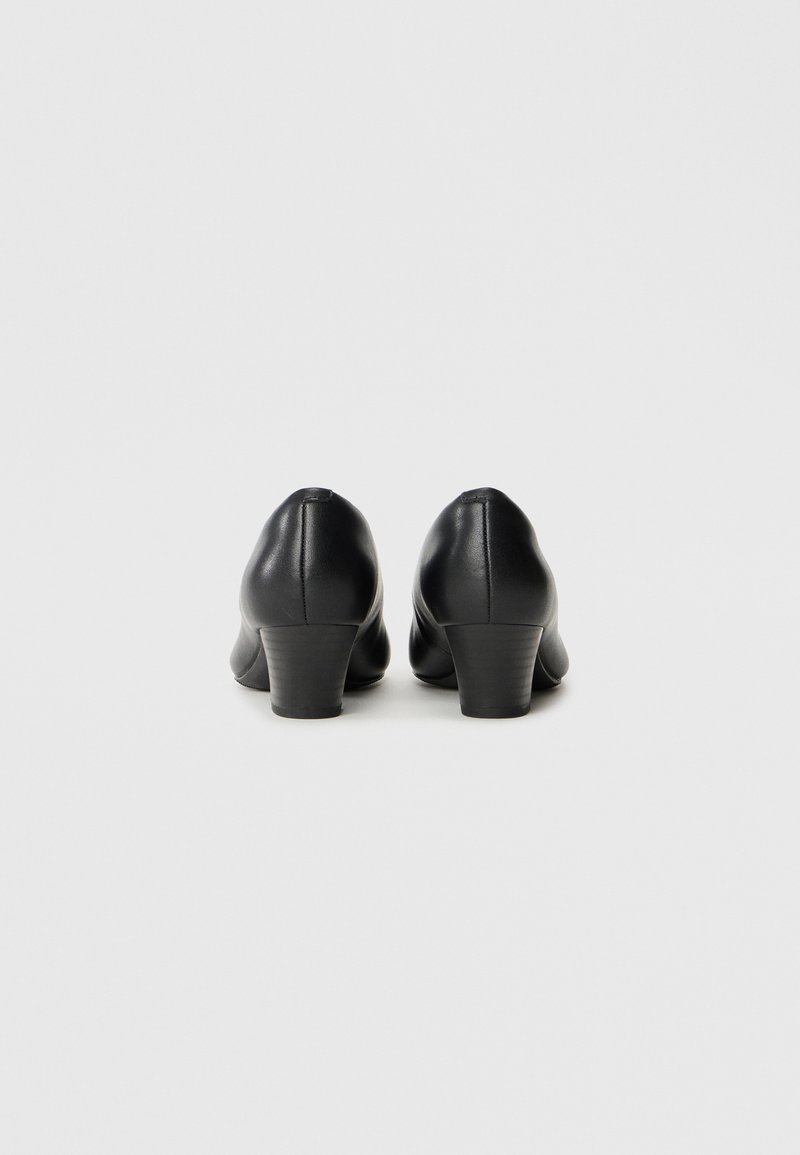 Chaussures à talons en cuir noir avec un bout arrondi et un talon carré modeste. Texture lisse avec un minimum de détails sur le talon et les côtés.