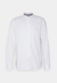 Camicia bianca a maniche lunghe con colletto alla francese, chiusura con bottoni frontale e piccolo logo sul petto. Realizzata in cotone con una texture liscia.