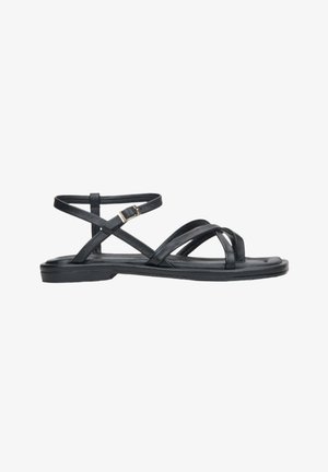 Schwarze Ledersandalen mit übereinander verlaufenden Riemen, einer verstellbaren Knöchelgeschnürung, flacher Sohle und glatter Oberfläche. Minimalistisches Design.