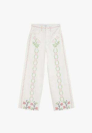 Vaqueros blancos de pierna ancha con bordado de punto de cruz floral en rosa y verde a lo largo de las piernas y costura en zigzag roja a los lados.