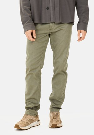 Olijfgroene katoenen broek met een slim fit en subtiele textuur, gecombineerd met lichtbruine sneakers met gaasaccenten en rubberen zolen.