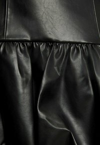 Tessuto in pelle sintetica nera con dettagli arricciati, caratterizzato da una superficie liscia e da una leggera lucentezza, che mostra pieghe arricciate e una morbida caduta.