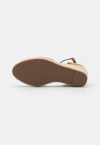 Sandalo espadrille marrone con suola in gomma testurizzata e sottopiede in juta intrecciata. Le cinghie presentano un semplice accento con fibbia.