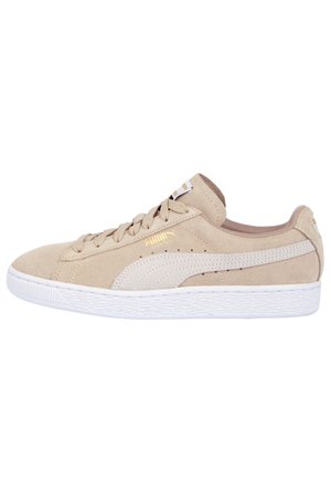 Jasnobeżowy zamszowy sneaker Puma z białą gumową podeszwą, beżowym paskiem Puma po boku, sznurowadłami i złotym logo Puma przy sznurowadłach.
