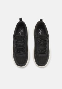 Schwarze Sneaker mit einem Obermaterial aus Mesh, ausgestattet mit einer leichten Sohle, Stoffsenkeln und einem Ziehband an der Ferse. Texturiertes Design für Atmungsaktivität.