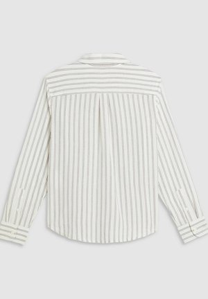 Chemise à rayures, base blanche avec de fines rayures rouges. Présente un pli au dos et des manches longues retroussées, fabriquée en tissu léger.