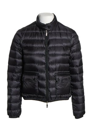 Chaqueta acolchada negra con cuello alto, cremallera frontal, dos bolsillos con solapa y botón, y puños y dobladillo elásticos.