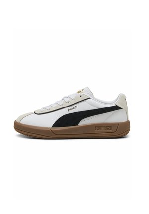 Zapatilla blanca Puma de perfil bajo con raya negra, suela color goma y detalles en dorado, vista de lado sobre fondo blanco.