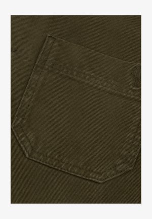 Tessuto in corduroy verde oliva scuro che mostra un primo piano di una tasca con una evidente texture a coste e cuciture dritte lungo i bordi.