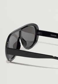 Mustad musta viimistlusega prillid, suured objektiivid ja sujuv disain. Omab tumedaid objektiive ja minimalistlikku esteetikat.