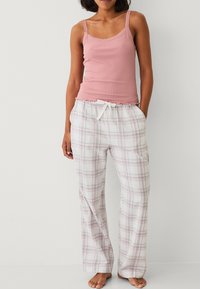 Rosa, mit Spitze verziertes Tanktop kombiniert mit weißen, karierten Schlafanzughosen, die pinke und graue Linien aufweisen, einen elastischen Bund und Seitentaschen haben.