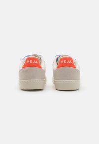 Weiße Veja-Sneaker mit grauen Wildlederakzenten und roten Logofersen. Mit blauen Details und einer beigen Gummisohle.