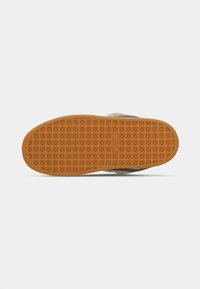 Sola do sapato apresentando uma base de borracha laranja texturizada com um padrão geométrico. Contraste de cor com a parte superior bege. Materiais de design robusto.