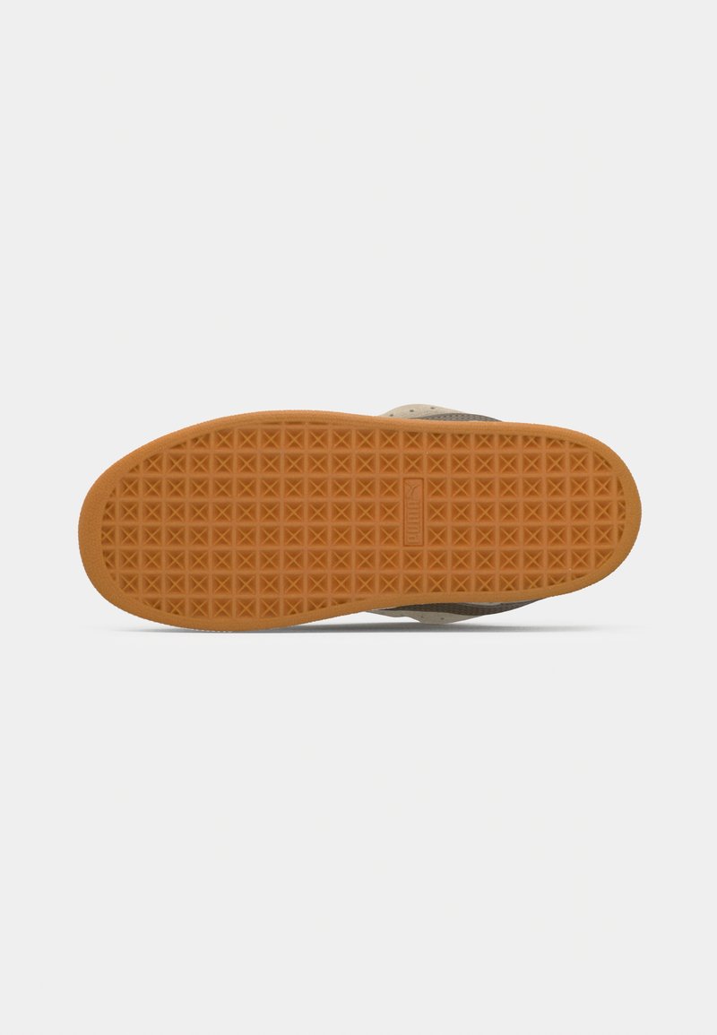 Suela de zapato con una base de goma naranja texturizada y un patrón geométrico. Contraste de color con la parte superior beige. Materiales de diseño robusto.