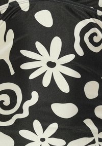 Tejido negro con un diseño floral y abstracto en contraste blanco, con grandes margaritas y espirales, textura suave y un acabado brillante.