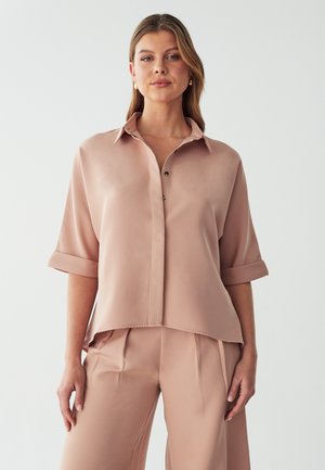 Blusa di seta rosa chiaro con colletto a punta, maniche arrotolate e chiusura a bottoni. Presenta una vestibilità comoda con un orlo curvato.