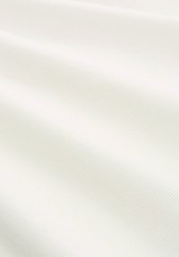 Close-up van glad, wit stof met subtiele diagonale geribbelde textuur en zachte plooien die zachte schaduwen creëren.