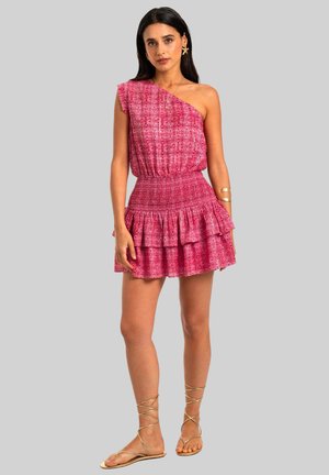 Vestido rosa de un solo hombro con un patrón floral, cintura fruncida y dobladillo de volantes en capas. Combinado con sandalias doradas de tiras y joyería mínima.