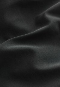 Tessuto nero con una texture liscia, che mostra lievi pieghe e una sottile lucentezza. La superficie è uniforme, senza motivi o dettagli aggiuntivi.