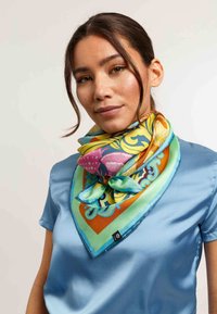 Zijden sjaal in levendige kleuren met een bloem- en abstract patroon; heeft een driehoekige vorm en een gladde textuur.