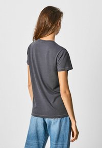 Gray, short-sleeve t-shirt with a round neckline and plain design. Fabric appears smooth, worn with light blue denim pants.