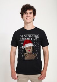 Černé bavlněné tričko s grafikou psa s červeným nosem a čapkou Santa, obklopené sněhovými vločkami a textem "JSEM NA SANTOVĚ ZLÉM SEZNAMU."
