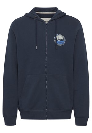 Marinblå zip-up hoodie med en kenguruficka, dragsko på huvan och cirkulär logodetalj. Mjuk bomullsblandning med långa ärmar och ribbade manschetter.