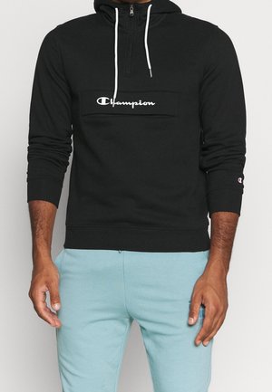 Felpa nera con cappuccio alto, design con zip a un quarto, logo Champion bianco sul petto e lacci a contrasto. Tessuto morbido e polsini aderenti.