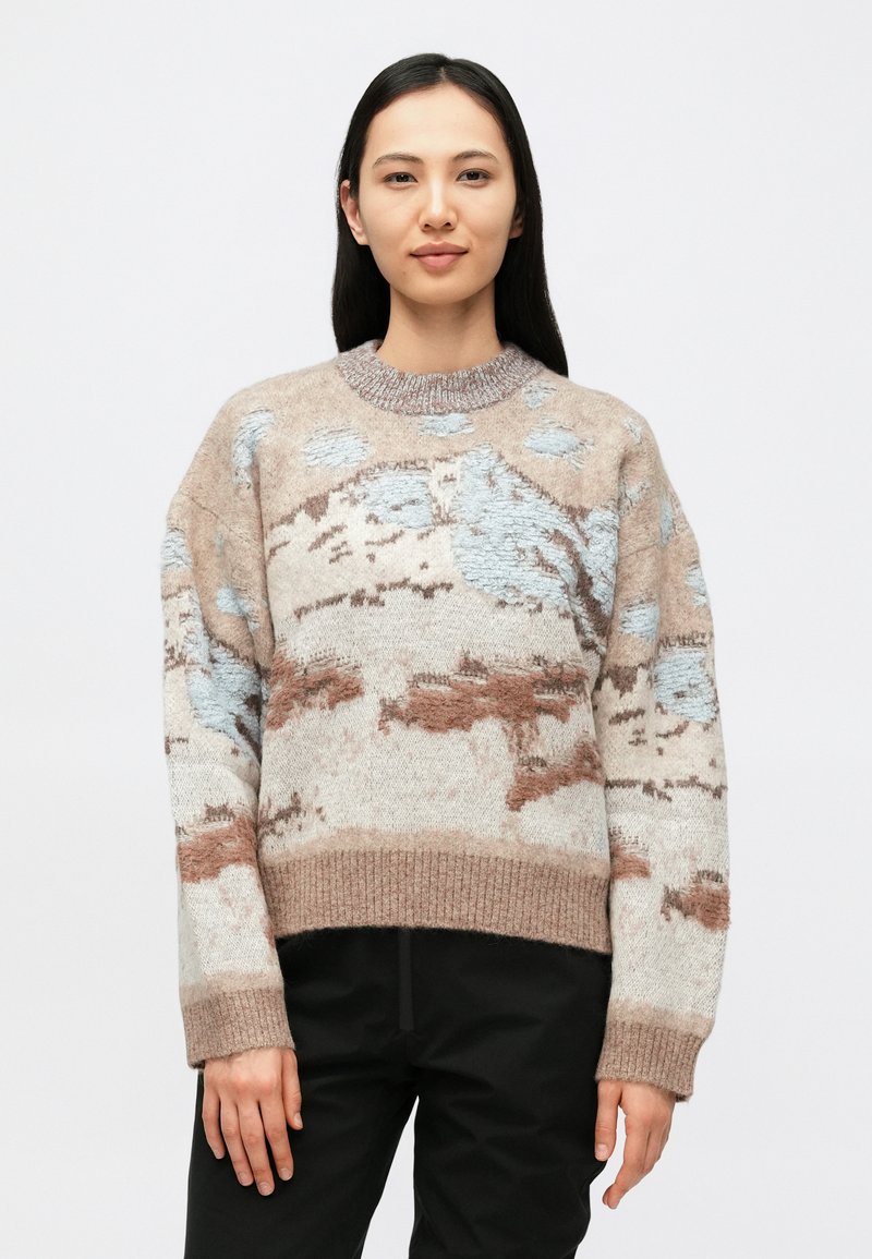 Kézzel kötött pulóver bézs színben, világoskék és rozsda mintákkal. Kerek nyakkivágással és bordázott szegéllyel rendelkezik. Puha, texturált felületű.