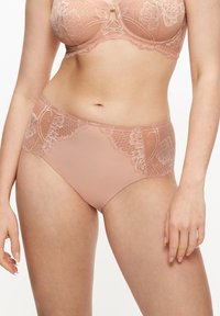 Tangas de color rosa pálido con encaje y detalles florales transparentes. Tejido suave y liso, con un corte de altura media y un diseño de cobertura total.