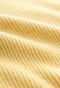 Nahaufnahme eines weichen, gelben Rippstoffs mit einer welligen Textur und sichtbaren Maschen, die diagonale Linien bilden.