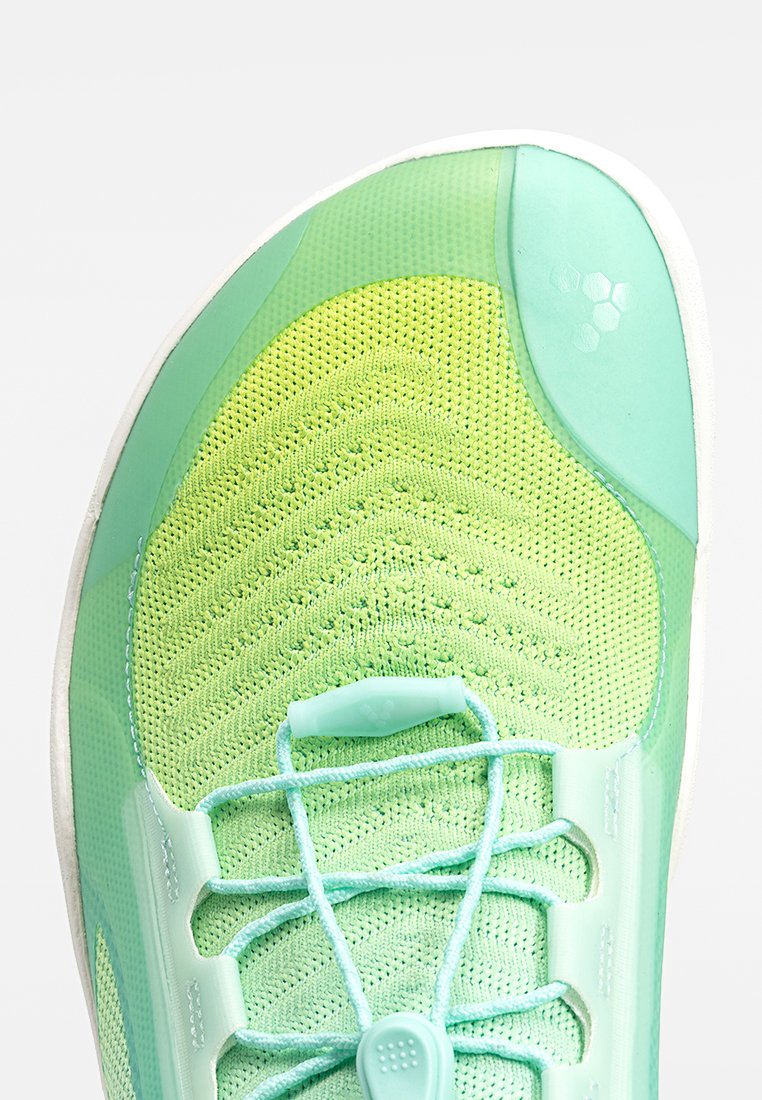 Zapatilla deportiva verde claro con parte superior de malla transpirable, patrón texturizado y diseño sin cordones que presenta un cierre de tipo toggle y una puntera reforzada.