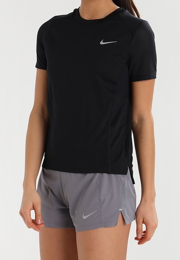 Camiseta atlética negra de Nike de manga corta con un diseño ajustado y acentos de malla, combinada con pantalones cortos grises de Nike que presentan una abertura y el logo.