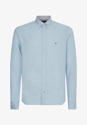 Vaaleansininen nappipaita kudotusta kankaasta, jossa on terävä kaulus, pitkät hihat ja pieni logo rinnassa.