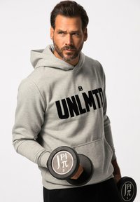 Sudadera gris con "UNLMTD" impreso en negro, presenta un bolsillo tipo canguro. La persona sostiene una mancuerna negra con una etiqueta de peso gris.