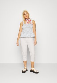 Top peplum floral com alças grossas, tecido leve; combinado com calças cropped cinza claro, ajustadas, e sandálias de plataforma cremosa com tiras.