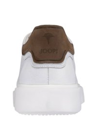 Białe sneakersy z fakturowaną skórzaną cholewką i brązowym zamszowym tabem na pięcie z wytłoczonym logo. Gruba biała gumowa podeszwa.