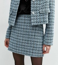 Tweed tvådelat set i ljusblått och svart, med en figursydd kjol och kort jacka med strukturerad tyg och silverknapp detaljer.
