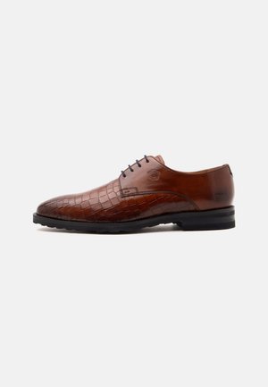Chaussure de ville pour homme en cuir marron avec motif crocodile à l'avant, lacets noirs et semelle noire, présentée en profil sur fond blanc.