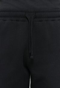 Sorte sweatpants har en elastisk linning med justerbar snøre og en blød, glat tekstur. Designet fremhæver komfort og pasform.