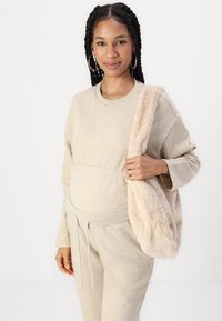 Ensemble de détente beige avec une coupe décontractée et une taille élastique, associé à un sac à épaule en peluche beige. Texture douce, design décontracté.
