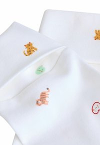 Biely bavlnený materiál s malými potlačami zvierat v žltej, zelenej a oranžovej farbe, obsahujúci design leoparda, mačky a usmievajúcej sa tváre.